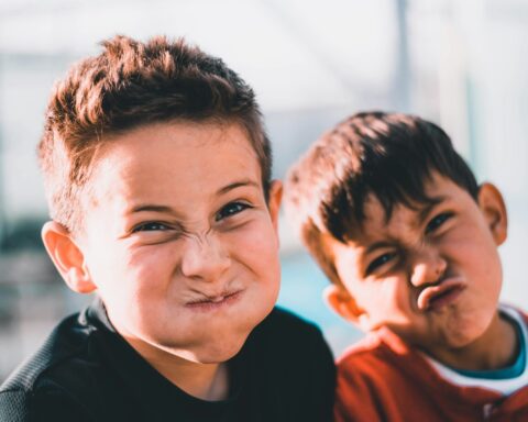 shallow focus photography of two boys doing wacky faces