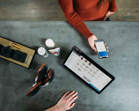 person holding smartphone beside tablet computer